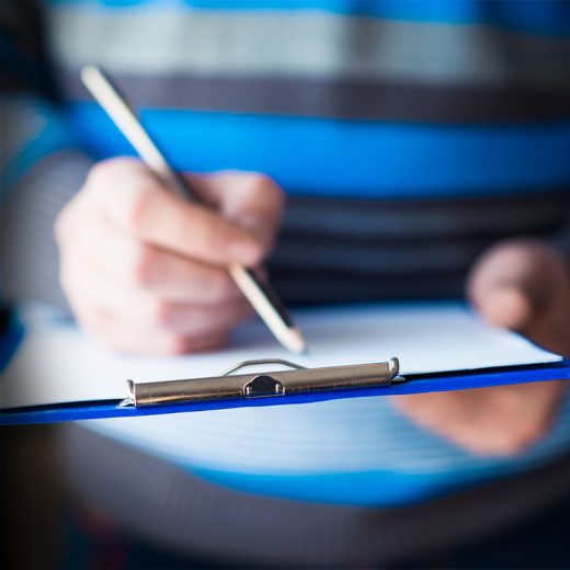 Person writing on clipboard